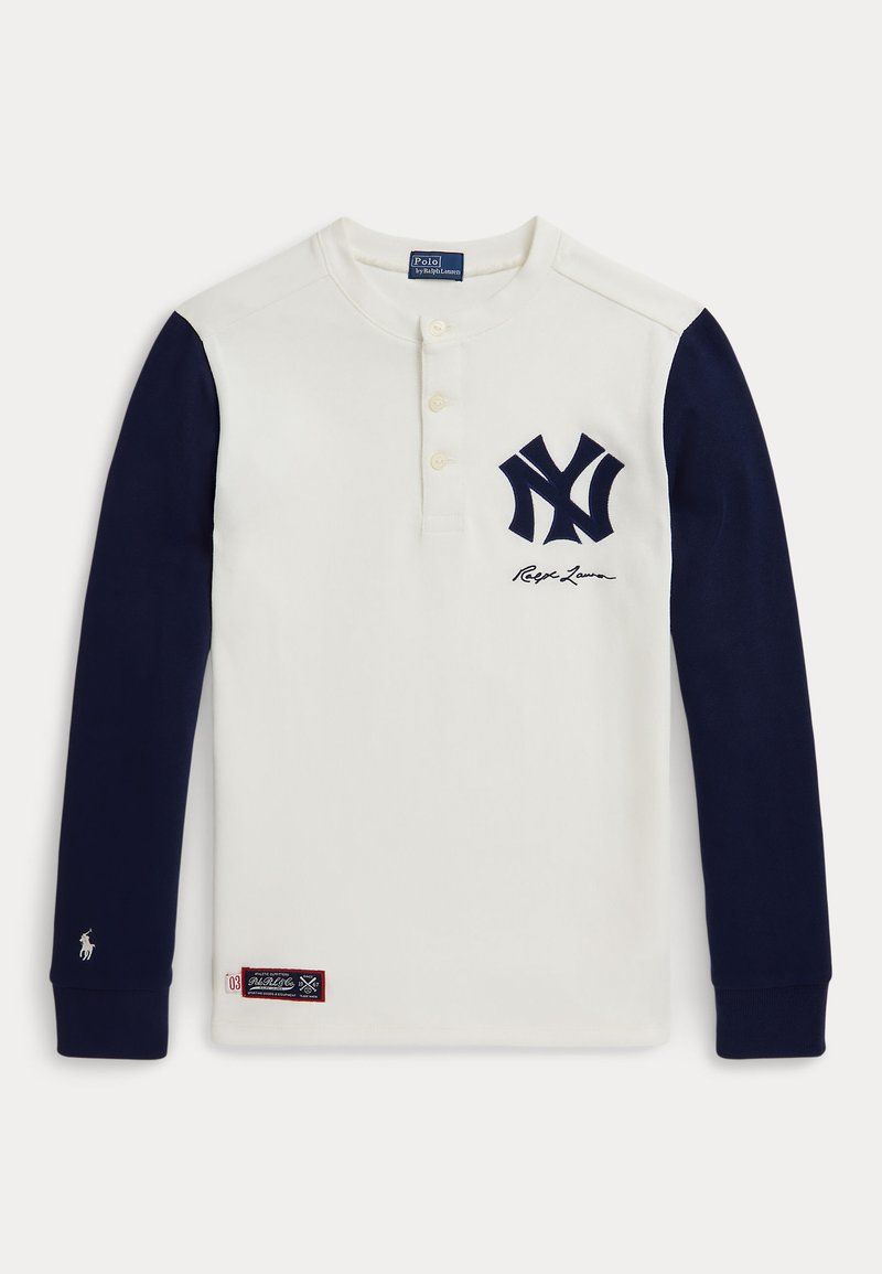 Langermet hvit skjorte med marineblå ermer, med en knappet krage, brodert NY-logo og Ralph Lauren-signatur. Rød merke-patch på kanten.