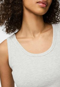Helles grau geripptes Tanktop mit weitem Ausschnitt und schmalen Trägern, das eine weiche Textur und ein minimales Design aufweist.