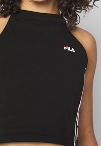 Top corto sin mangas negro de algodón, con un cuello alto y el logo de Fila bordado en rojo y blanco en el lado izquierdo del pecho.