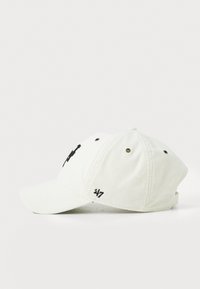 Valge korduroy müts, millel on kumer visor, must logo tikand ees ja kontrastsed õmblused. Reguleeritav tagune rihm.