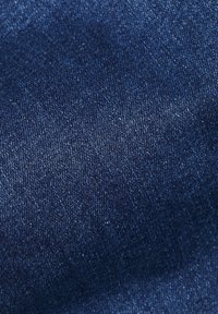 Tela de mezclilla azul oscura con una textura suave, que presenta sutiles variaciones de color y un patrón de tejido clásico en toda su superficie.