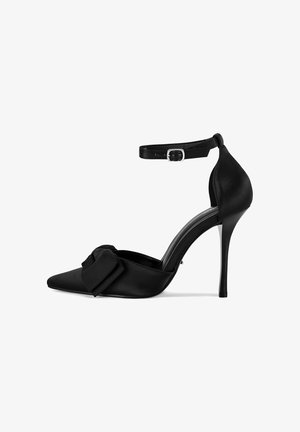 Czarna szpilka z ostrym noskiem, wykonana z satyny, z paskiem wokół kostki i dekoracyjną kokardą z przodu. Gładka tekstura i błyszczący obcas.