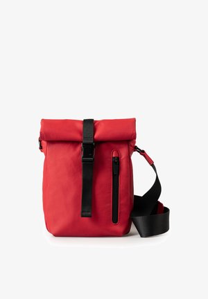 Red roll-top backpack with black buckle, vertical front zipper pocket, and adjustable black shoulder strap against white background.