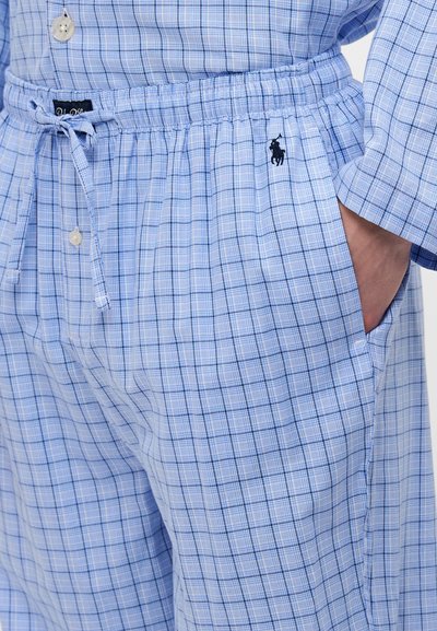 Ensemble de pyjama à motif à carreaux bleu clair en coton. Caractéristiques : taille élastique avec cordon de serrage, poches latérales et petit logo brodé sur le côté gauche.