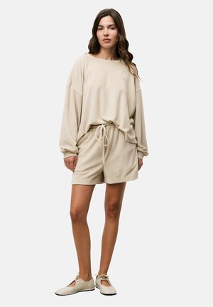 Beige Oversized-Sweatshirt mit fallenden Schultern und passender Shorts, beide aus weichem Stoff mit verstellbarem Bund und schlichter Optik.