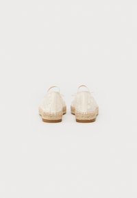 Scarpe espadrillas bianche in pizzo con forma arrotondata, suole in corda di juta naturale e retro in pelle liscia. Dettaglio in un delicato motivo di pizzo.