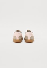 Des baskets en cuir suédé combinant un rose doux et un taupe, avec une semelle en caoutchouc translucide. "Alo Sport Club" est embossé en doré.