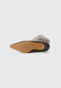 Stivale marrone con tacco, punta affusolata, tomaia in pelle liscia e suola in gomma testurizzata. Il design presenta una silhouette elegante e hardware minimo.