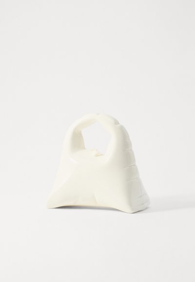 Hvidt keramisk tilbehør med et bøjet håndtag og struktureret greb. Basen er bred, der taper opad, og har en glat, blank finish.