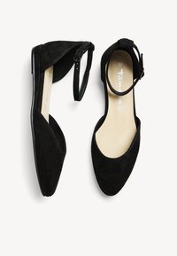 Ballerines en daim noir avec bout arrondi, bride à la cheville et semelle intérieure couleur chair, présentant une texture lisse et un design minimaliste.