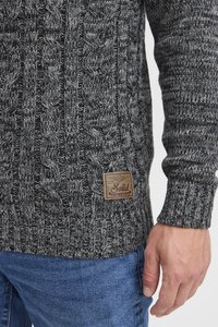 Gruby sweter dziany w ciemnoszarym i czarnym kolorze z wzorami warkoczy. Posiada materiałową naszywkę z napisem "Solid" po dolnej stronie.