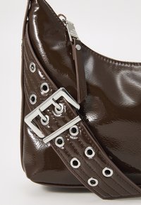 Borsa a tracolla in pelle verniciata marrone con ampia tracolla regolabile, dotata di fibbia e occhielli in argento, e zip pull tab abbinato.