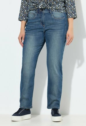 Jeans in denim blu con una vestibilità a gamba dritta, dotati di tasche frontali e una leggera scoloritura. Abbinati a sneakers con platform blu navy.