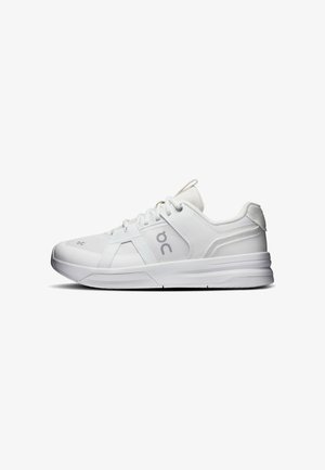 Baskets blanches de sport avec panneaux en mesh et cuir, fermeture à lacets et semelle épaisse, vues de côté sur fond blanc.