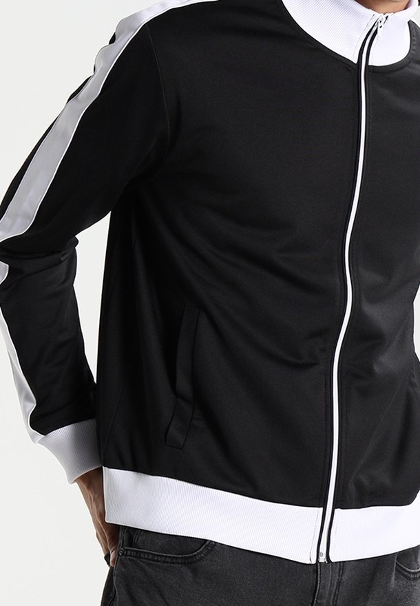 Black zip-up jacket with white accents and ribbed cuffs. Features a high collar and side pockets. Made from smooth, flexible fabric.