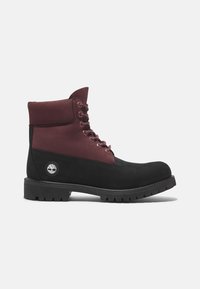Bottines de randonnée noires et bourgogne en daim et cuir, avec des œillets en métal, un col rembourré et une semelle en caoutchouc texturé.