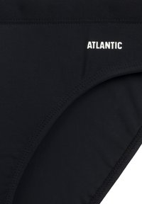 Czarny dół bikini wykonany z gładkiego, elastycznego materiału. Wyposażony w przeszywane krawędzie oraz białe logo "ATLANTIC" z przodu.
