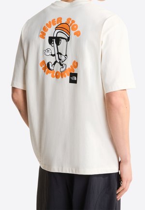 Personne portant un t-shirt blanc avec un personnage de mousqueton en dessin animé et un texte orange "Never Stop Exploring" dans le dos.