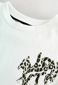 Hvid crew neck t-shirt med et sort og gråt leopardmønster logo design delvist synligt på brystet.