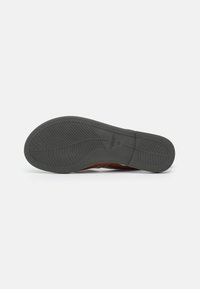 Semelle de chaussure en cuir marron avec une bande de roulement en caoutchouc texturé. Présente une légère courbure et des motifs de crampons proéminents pour une meilleure traction.