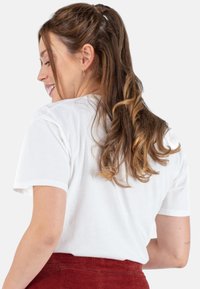 Witte katoenen t-shirt met korte mouwen, een ronde hals en een relaxed fit, gedragen met een rode corduroy rok, die een gladde textuur toont.