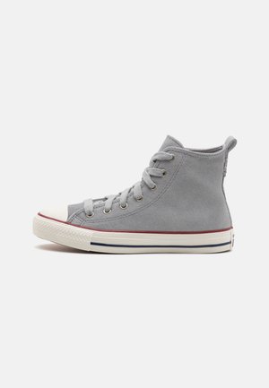 Grå højt sneakers med hvid gummisål, røde og blå striber, hvid tåhætte og grå snørebånd på ensfarvet baggrund.