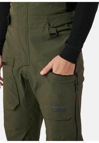 Waterdichte olijfgroene skibroek met meerdere zakken en een ritsvak aan de zijkant, uitgerust met een logo en een verstelbare tailleband.