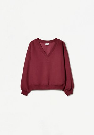 Sweatshirt en V bordeaux avec coupe décontractée, poignets et ourlet côtelés. Tissu doux, manches larges, design minimaliste sans motifs visibles.