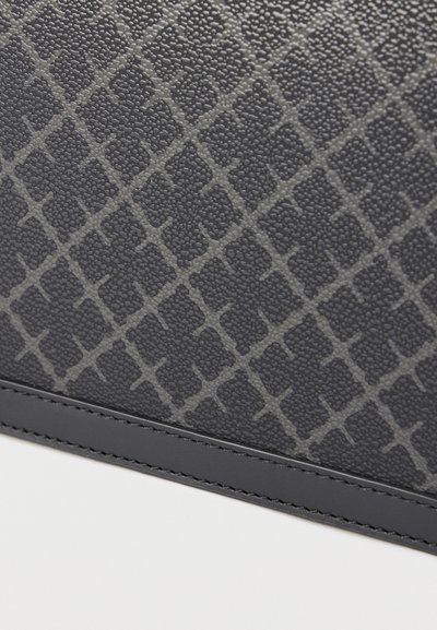 Μαύρη τσάντα από δέρμα με υφή που διαθέτει ένα διακριτικό γεωμετρικό μοτίβο, ομαλές άκρες και ραφές κατά μήκος του κάτω μέρους.