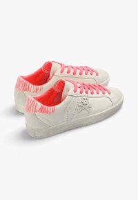Baskets en cuir blanc avec des lacets roses et des accents rayés sur le talon. Présente un logo de skull et une semelle texturée de couleur gris clair.