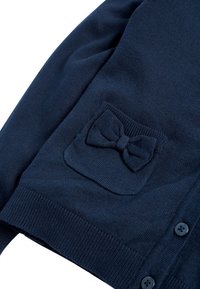 Marineblauer Cardigan aus weichem Strickmaterial, mit einer aufgesetzten Tasche mit Schleifendetail und Knopfverschluss an der Vorderseite.