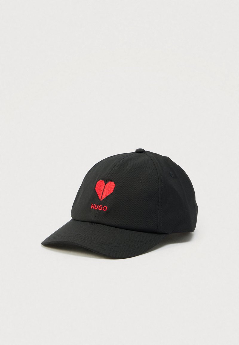 Black baseball cap with red origami-style heart and "HUGO" embroidered on front, set against a plain white background.