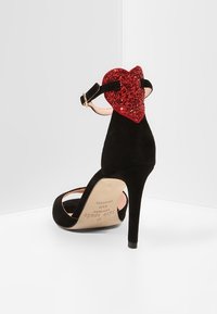 Czarne zamszowe sandały na wysokim obcasie z zapięciem na kostce i czerwonym, brokatowym serduszkiem na tyle.