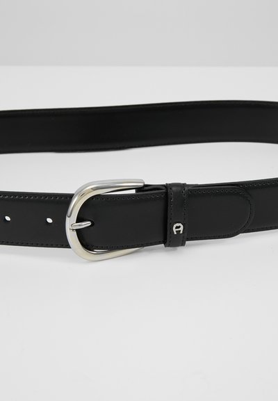 Cinturón de cuero negro con hebilla de metal plateado, textura suave y agujeros espaciados uniformemente para ajustar el tamaño. Sutil acento de logo en el cuero.