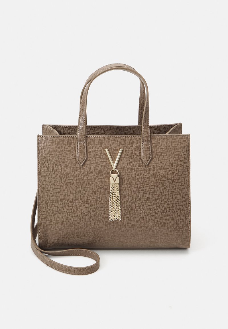 Bolsa tote texturizada marrom com duas alças e uma alça destacável. Apresenta um detalhe em forma de V em tom dourado e um detalhe de franjas metálicas.