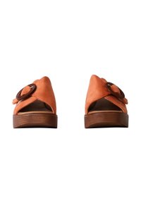 Orange suede sandals with an open toe design, featuring a large circular brown accent and a wooden sole.