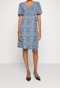 Blå mönstrad omlottklänning med korta ärmar, V-ringning och knytband i midjan; över knä-längd; lättviktsmaterial.