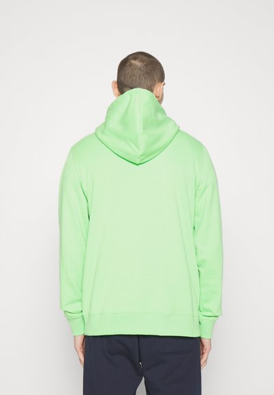 Grønn hettegenser med snorhette, lange ermer og en myk tekstur. Har ribbestrikkede mansjetter og nederkant, sett fra baksiden.