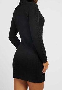 Robe-sweater noire en tricot avec un col montant, des détails en maille torsadée sur les manches, une silhouette près du corps et des poignets côtelés, mettant en avant une finition texturée.