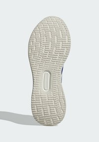 Suela de zapato deportivo con una superficie texturizada y con patrón. Principalmente de goma blanca con surcos y elementos de tracción detallados.