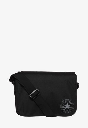 Borsa a tracolla nera realizzata in tessuto durevole, dotata di una pattina frontale, tracolla regolabile e un'etichetta con logo circolare decorata con un design a stella.