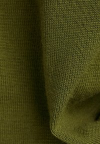Olivgrüner Strickstoff mit einer fest gewebten Textur, feinen, gleichmäßigen Stichen und einem subtilen Glanz, gefaltet, um Tiefe und Weichheit zu zeigen.