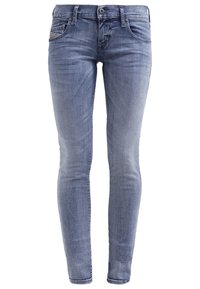 Jean slim fit en denim bleu avec fermeture devant par bouton et zip, design cinq poches et légère décoloration aux cuisses et aux genoux.