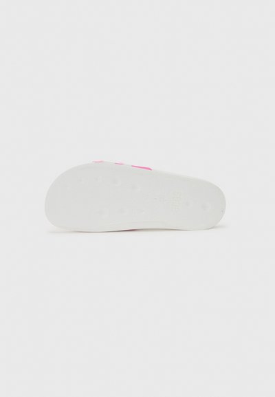 Shoe sole with a textured white rubber surface, featuring pink accents and circular grips for traction. Clean and minimalist design.