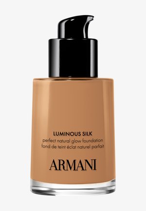 Fond de teint Luminous Silk dans un flacon en verre transparent avec un bouchon-pompe noir. Liquide hâlé avec marquage et détails du produit en texte noir.