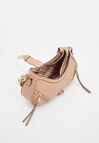 Sac à bandoulière en cuir beige avec quincaillerie dorée, deux poches zippées, sangle large et doublure intérieure en tissu imprimé.
