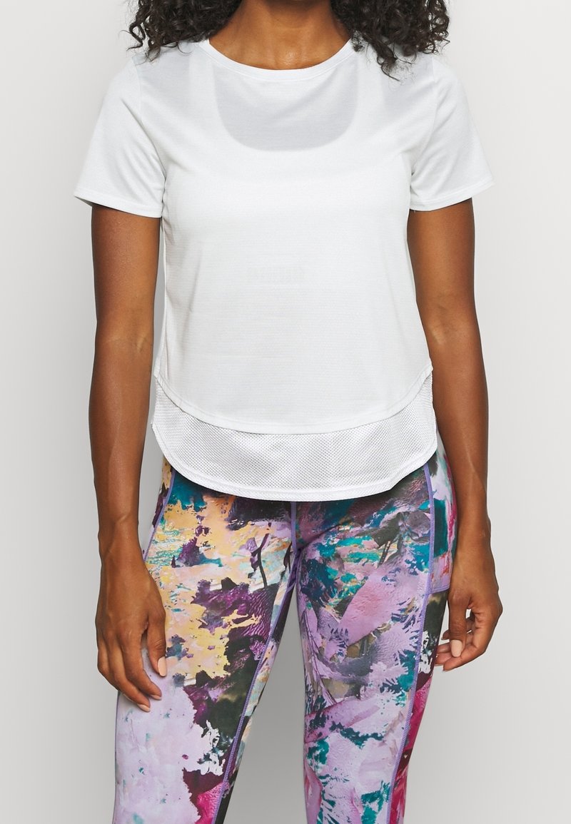 Vitt(idrotts)t-shirt med rund halsringning och nätfåll. Kombinerat med flerfärgade leggings med abstrakt mönster som har rosa och blå nyanser.