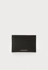Sort læderkortholder med en tekstureret finish, der har tre kortpladser, diagonale striber og et hvidt Lacoste-logo nederst.