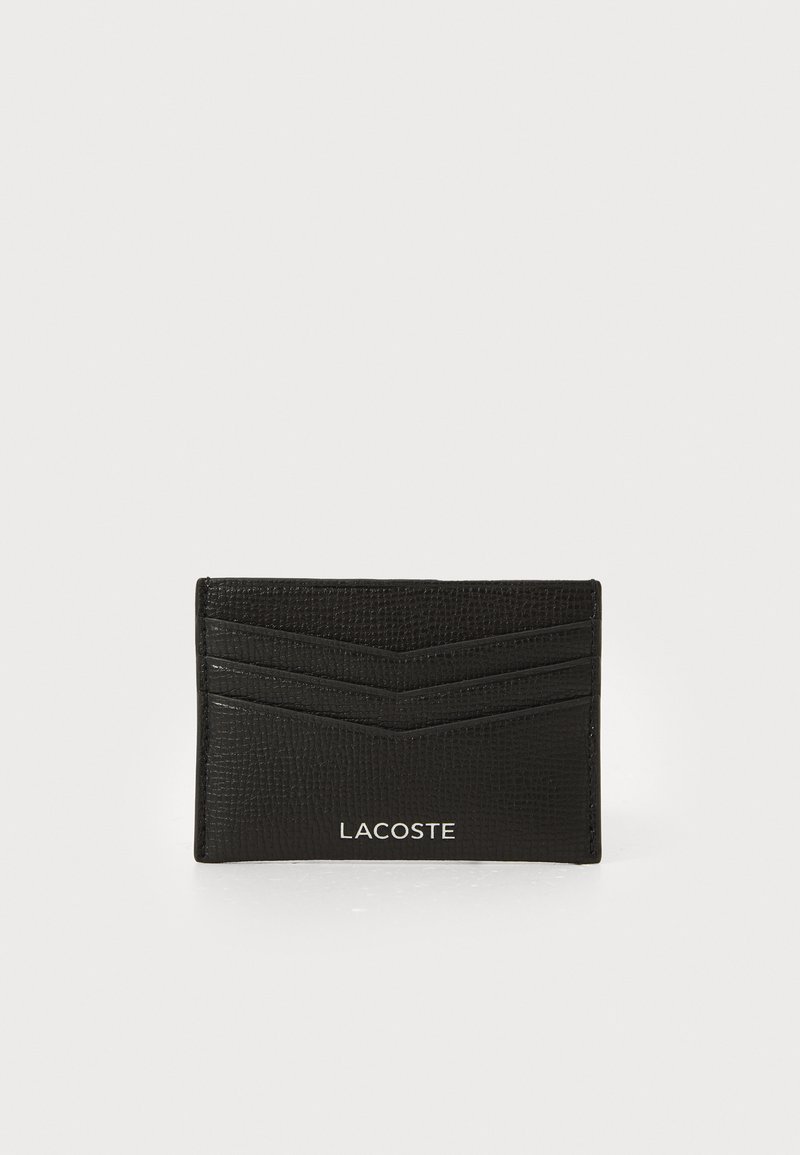 Sort læderkortholder med en tekstureret finish, der har tre kortpladser, diagonale striber og et hvidt Lacoste-logo nederst.