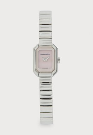 Montre en métal argenté avec un boîtier octogonal, un cadran rose et un bracelet élégant et texturé comprenant des segments alternant polis et rainurés.